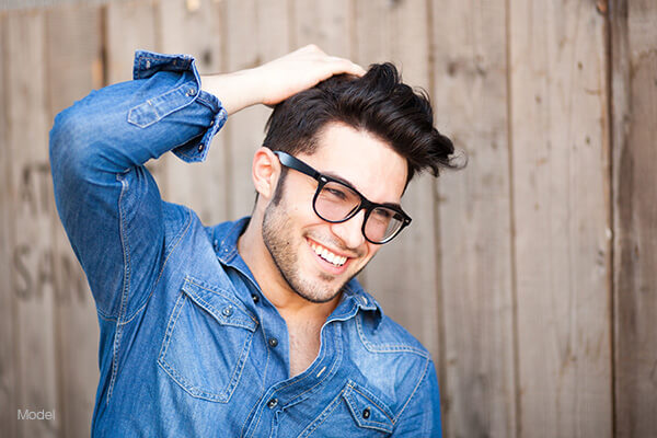 Man with glasses running his hand through his hair